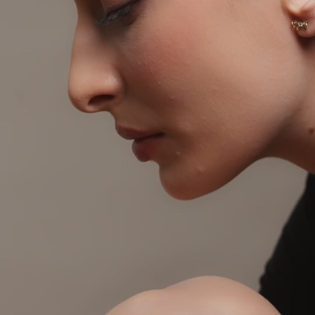 Model wearing 14K gold bowtie stud earrings, showing how the dainty bow design adds a touch of charm and timeless elegance to her everyday look.