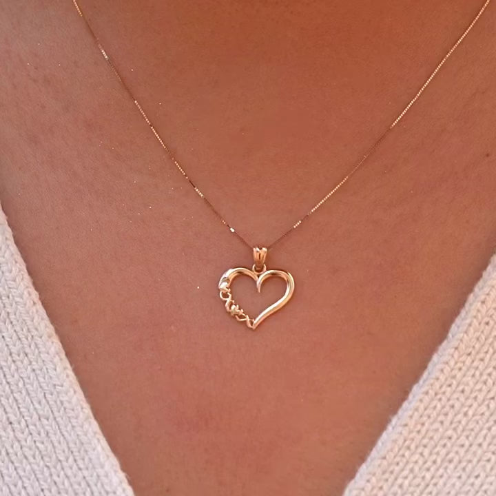 Video of Model wearing a delicate 14K gold heart charm on a dainty chain, the pendant resting gracefully near the collarbone.