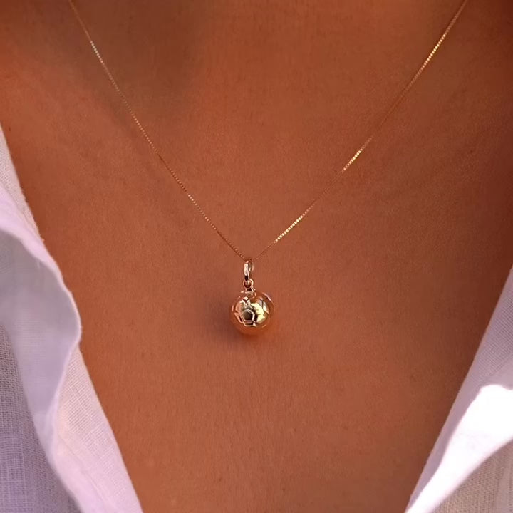 Model wearing 14K yellow gold soccer ball pendant on a thin chain, styled as a sporty-chic necklace.