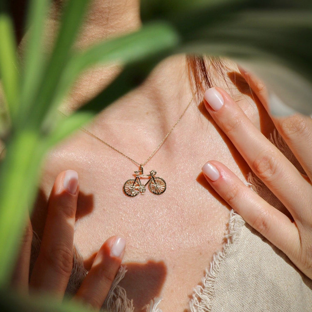 Model wearing the 14K Solid Gold Bicycle Charm on a chain, captured from a slightly distant view to highlight its dainty size and elegant appearance.