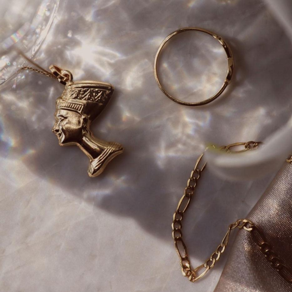 14K Real Gold Nefertiti Charm on a chain, displayed in a live setting to highlight its elegant design and polished finish.
