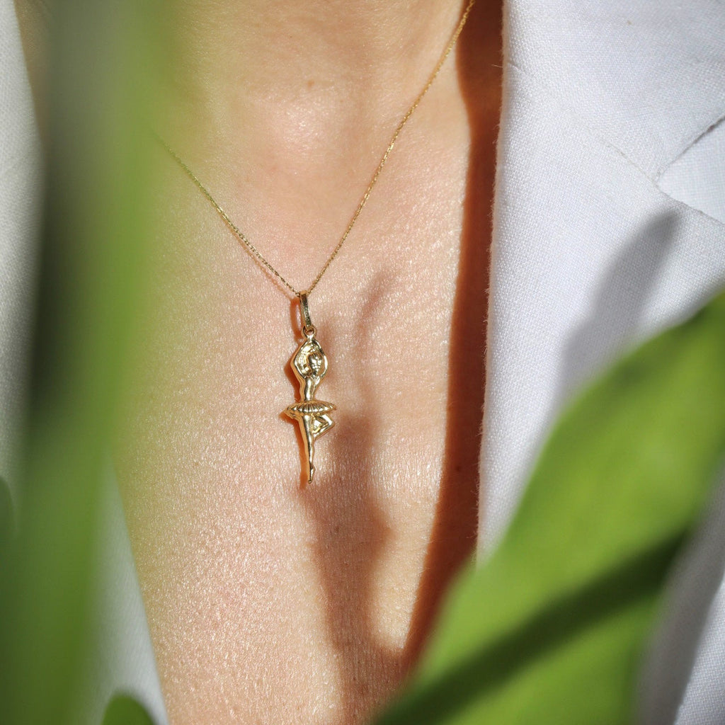Close-up of a model wearing the 14K Solid Gold Ballerina Charm on a chain, highlighting its intricate details and polished yellow gold finish.